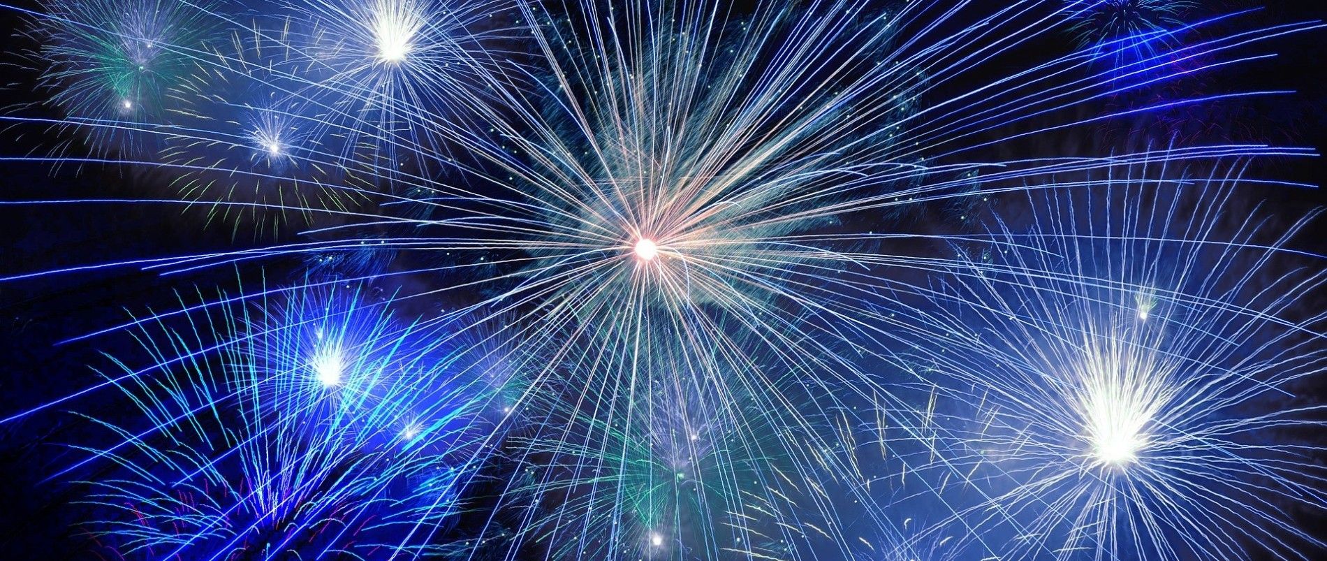 Blau und weiß leuchtende Feuerwerkskörper am Nachthimmel.