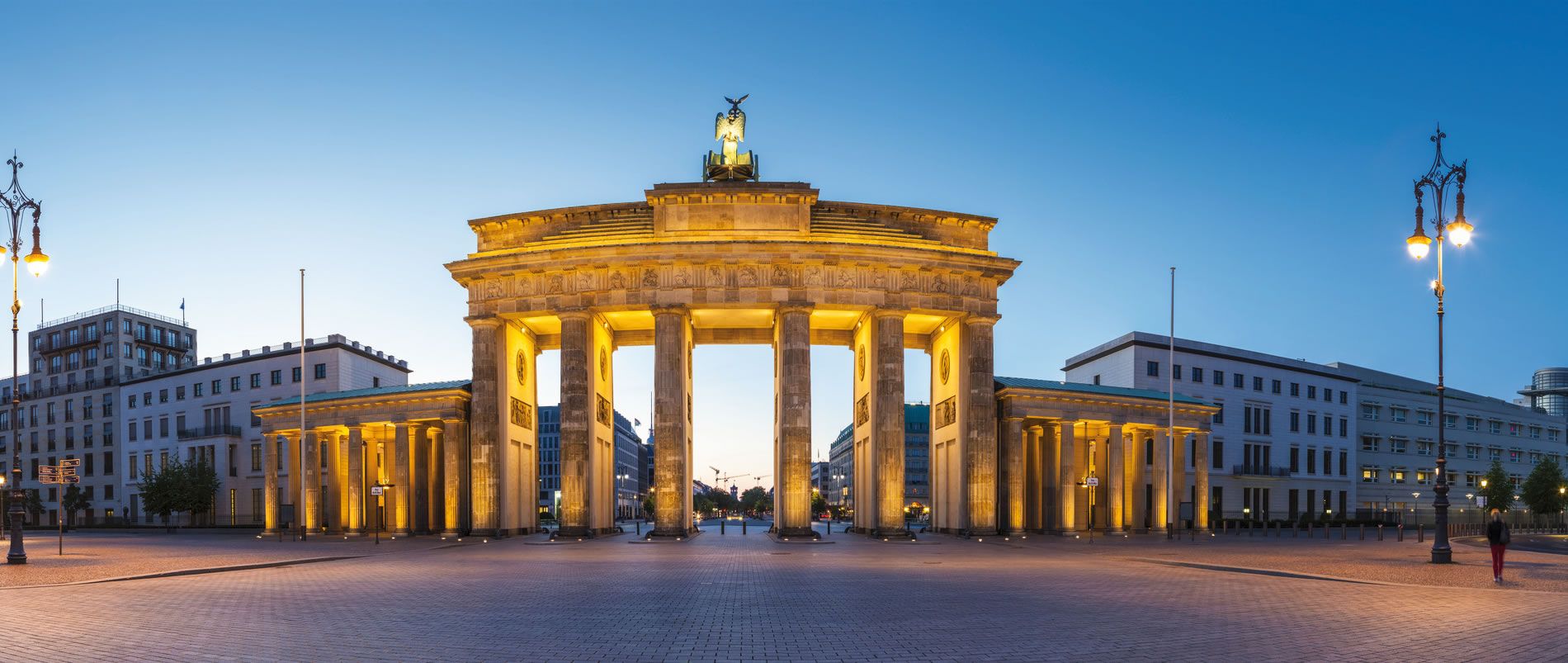 Das beleuchtete Brandenburger Tor in Berlin bei Sonnenaufgang.