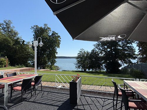 Glasüberdachung eines Gebäudes mit Blick auf einen See und Bäume im Hintergrund